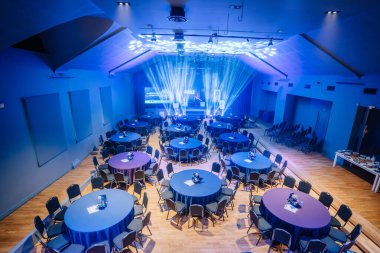 Valmiera, Letonya - 18 Ekim 2024 - yapay zeka konferansı. Yuvarlak masalar ve sahne ışıklarıyla bir konferans salonu, sunumlar ve konuşmalar için hazır..