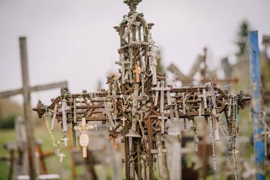 Siauliai, Litvanya, 21 Ekim 2024 Kryzi Kalnas. Daha küçük haçlar, boncuklar ve dini sembollerle süslenmiş, inanç, dua ve bağlılığı simgeleyen büyük bir haçın yakın çekimi..