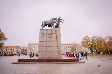 Vilnius, Lithaunia - 22 Ekim 2024 - Bulutlu bir günde turistlerin toplandığı şehir meydanında büyük bir binicilik heykeli.