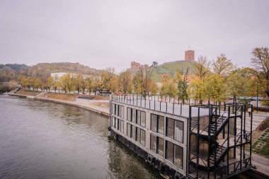 Vilnius, Lithaunia - 22 Ekim 2024 - Sonbahar boyunca arka planda tepe ve Gediminas Kulesi manzaralı modern yüzer bina.