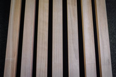 A close-up view of a wooden slatted surface, with evenly spaced light-colored wood planks and dark gaps in between. clipart