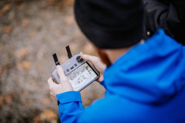 Smiltene, Letonya - 27 Ekim 2024 İHA uzaktan kumandalı mavi ceketli bir adam, ekranda gösterilen hava görüntülerini yakalıyor..