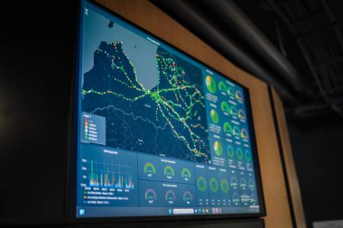 Riga, Latvia - October 25, 2024 - A large screen displays a real-time network map with charts and graphs monitoring data metrics, connectivity, and call setup performance. clipart