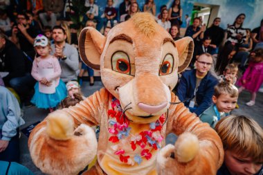 Riga, Letonya - 25 Ekim 2024 - Aslan kostümlü bir maskot, heyecanlı çocuklar ve yetişkinlerle çevrili bir Peter Pan partisinde eğlenceli ve neşeli bir ortam yaratarak çocukları eğlendiriyor..