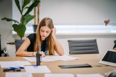 Riga, Letonya - 25 Ekim 2024 - Genç bir kız PETER PAN Parti sırasında kağıt ve kalemlerle bir masada yazmaya odaklanıyor..