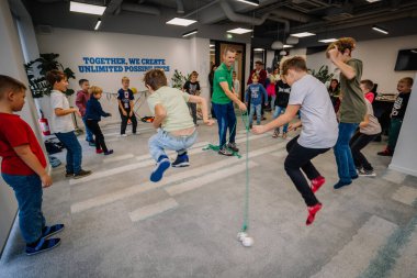 Riga, Letonya - 25 Ekim 2024 - PETER PAN Partisinde çocuklar hareketli bir grup oyunu sırasında sallanan bir topun üzerinden atlayıp kapalı bir alanda eğleniyorlar..