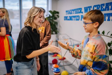 Riga, Letonya - 25 Ekim 2024 - Bir kız ve oğlan PETER PAN Partisinde el çırpma oyunu oynuyor, diğerleri arka planda yer alırken, diğerleri eğleniyor ve etkileşime giriyor.