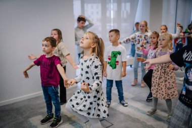 Riga, Letonya - 25 Ekim 2024 - Bir grup genç çocuk bir PETER PAN Partisinde coşkuyla bir etkinliğe katılıyor, hareketleri takip ediyor ve kapalı alanda eğlenceli bir çevreye giriyorlar..