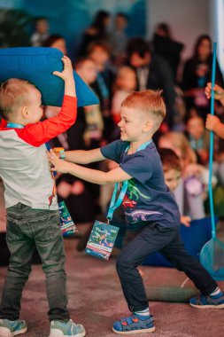 Riga, Latvia - October 25, 2024 -  Two young boys playfully fight with a pillow at a lively Peter Pan Party, surrounded by other children in a fun and energetic environment. clipart