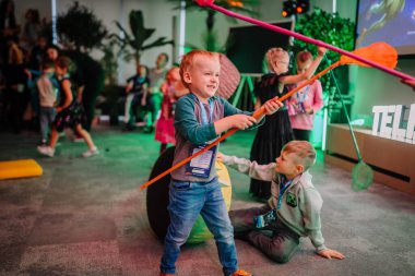 Riga, Latvia - October 25, 2024 - Children play with colorful toys at a lively Piter Pan Party, engaging in fun activities indoors with joyful expressions and energy. clipart