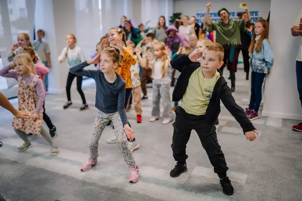 Riga, Letonya - 25 Ekim 2024 - Bir grup çocuk canlı bir PETER PAN partisinde aktif olarak dans veya hareket etkinliğine katılıyor, kapalı alanlarda birlikte eğleniyorlar ve eğleniyorlar.