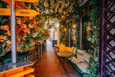 Vilnius, Lithaunia - 22 Ekim 2024 - Canlı turuncu ve yeşil süslemeleri, yön işaretleri ve tuğladan yapılmış kaldırım üzerinde büyüleyici bir oturma alanı olan açık hava kafesi köşesi