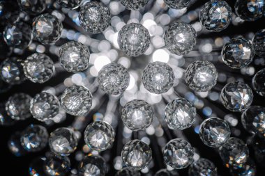 Bir avizeye yerleştirilmiş çoklu kristal kürelerin yakın plan görüntüsü, arka planda Bokeh ışıkları ile ışıltılı ve yansıtıcı bir etki yaratıyor..