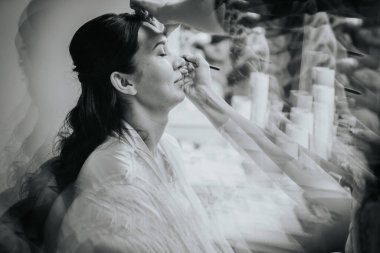 Koknese, Latvia - September 26, 2023 - A black-and-white artistic shot of a woman getting makeup applied, with a prism effect creating layered reflections, adding a dreamlike, ethereal quality. clipart