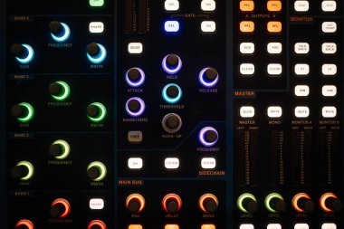 Valmiera, Letonya - 18 Kasım 2024 - Aydınlatılmış düğmeler, düğmeler ve ses ayarları için denetimler ile bir ses karıştırma konsolunun yakın plan görüntüsü.