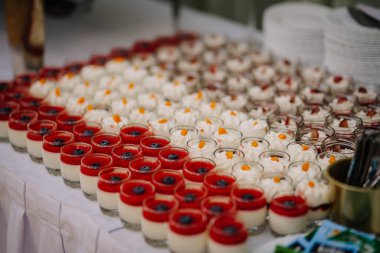 Aloja, Latvia - November 16, 2024 - A table filled with colorful desserts in glass jars, including panna cotta with berry sauce and whipped cream, ideal for catering or events. clipart