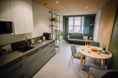 Valmiera, Letonya - 18 Kasım 2024 - Kanepesi, yuvarlak masası, sandalyeleri ve bitkileri olan modern mutfak ve yemek alanı. Konforlu, işlevsel ve şık iç tasarım.