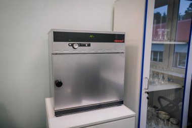 Valmiera, Letonya - 18 Kasım 2024 - 20C 'de dijital ekranı olan laboratuvar inkübatörü, laboratuvar ekipmanları ve laboratuvar ekipmanlarıyla birlikte cam bir dolabın yanına yerleştirildi.