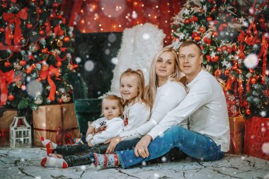 Güzel dekore edilmiş bir Noel ağacının yanında oturan bir çift. Etrafı şenlikli süsler, hediyeler ve hoş bir tatil dekoruyla çevrili..