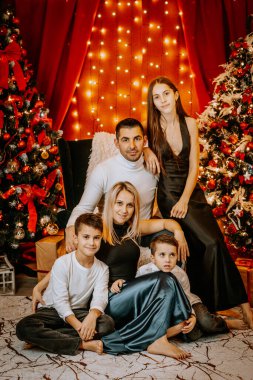 Noel ağaçları, ışıklar ve dekorasyonlarla dolu sıcak bir aile portresi, beraberlik ve tatil ruhu sergileniyor..