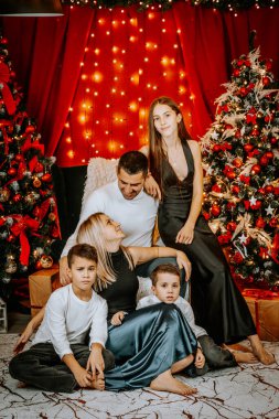 Noel ağaçları, süsler ve ışıklarla dolu bir ortamda birlikte poz veren bir aile. Sevgiyi, birlikteliği ve tatil ruhunu gösteren bir aile..