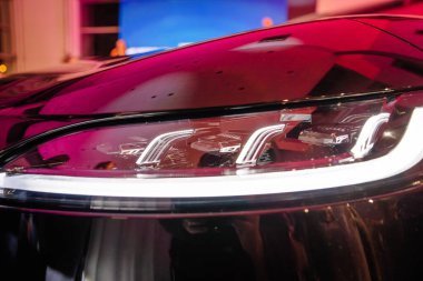 Riga, Letonya - 2 Aralık 2024 - Dongfeng arabalarının yakın çekimleri fütüristik LED tasarımı ve teşhir odası aydınlatması altında yansıtıcı detaylar sergileniyor