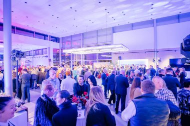 Riga, Letonya - 2 Aralık 2024 - Büyük bir kalabalıkla hareketli bir etkinlik arka planda Drive Your Dreams markalaşmasının yer aldığı modern, aydınlık bir sergi salonunda toplandı