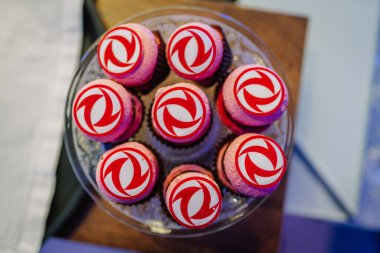 Riga, Letonya - 2 Aralık 2024 - Üzerinde kırmızı ve beyaz Dongfeng logoları olan yakın plan pembe makaronlar profesyonel bir etkinlikte cam bir tabakta sergilendi.