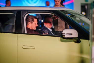 Riga, Letonya - 2 Aralık 2024 - Dongfeng arabasında oturan iki adam, biri canlı ışıklandırmalı ve modern bir otomotiv seti olan bir şarap kadehi tutuyor..