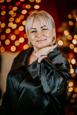 Close-up portrait of a confident woman with blonde hair posing against a festive red background with golden bokeh lights. clipart