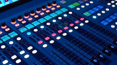 Aydınlatılmış bir ses karıştırma konsolunun bir stüdyoda sürgüler, düğmeler ve düğmelerle yakın plan görüntüsü veya canlı performans ayarları.