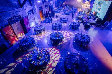 Riga, Letonya - 11 Ocak 2025 - Süslü yuvarlak masalar, zarif ışıklandırma ve ekranda Buz Diyarı 'nın yer aldığı büyük bir etkinlik salonunun genel görünümü