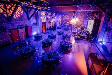 Riga, Letonya - 11 Ocak 2025 - Süslü yuvarlak masalar, zarif ışıklandırma ve ekranda Buz Diyarı 'nın yer aldığı büyük bir etkinlik salonunun genel görünümü