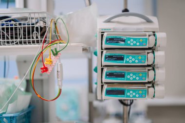 Valmiera, Letonya - 17 Ocak 2025 - B Braun infüzyon pompa sisteminin yakınlarda renkli EKG kabloları asılı, hasta bakımı için klinik hastane ortamında kullanılıyor..