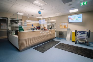 Valmiera, Letonya - 17 Ocak 2025 - Temiz bir ortamda modern hastane resepsiyon alanı, cam bölmeler, bilgilendirme gösterileri, oturma ve tıbbi ekipmanlar.