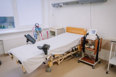 Valmiera, Letonya - 17 Ocak 2025 - Jinekolojik yatak, tıbbi ekipman ve monitörlü tıbbi muayene odası, temiz ve parlak bir klinik ortamında.