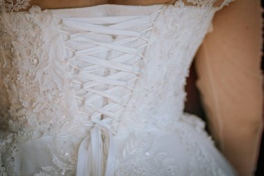 A close-up of the back of a lace wedding dress with intricate embroidery and a corset-style ribbon tie, showcasing delicate and elegant details. clipart