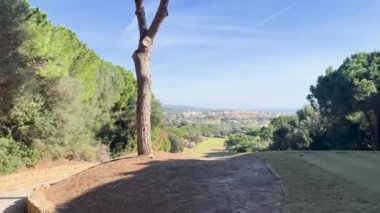 Sotogrande, İspanya - 26 Ocak 2024 - Ağaçlı bir golf sahasının manzarası, uzak bir kasaba, ve doğal yeşillik çerçeveli açık mavi bir gökyüzü.