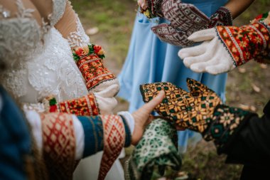 Valmiera, Letonya - 16 Ağustos 2024 - Kültürel törenler ya da açık hava festivalleri sırasında renkli, desenli geleneksel örgü eldivenler giyen ellerin yakın çekimi.