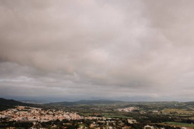 Sotogrande, İspanya - 26 Ocak 2025 - Sarsılan tepeler, yemyeşil yemyeşil ve bulutlu gökyüzü ile çevrili küçük bir kasabanın havadan görünüşü, barışçıl ve manzaralı bir kırsal alan yaratıyor..