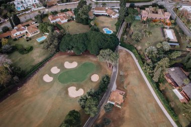 Sotogrande, İspanya - 26 Ocak 2025 - Kum sığınakları, yeşil çimenler, ağaçlarla kaplı patikalar, havuzları ve bahçeleri olan lüks villalar.