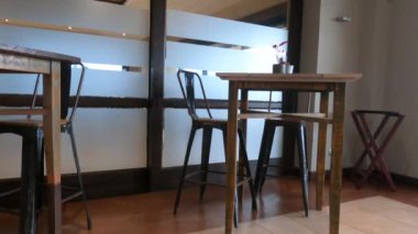 Modern tasarımda ahşap masalar, metal sandalyeler ve buzlu cam bölmeleri olan bir kafe ya da yemek alanının minimalist iç görünüşü.