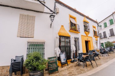 Gaucin, İspanya - 27 Ocak 2025 - Gaucin 'de açık bir kafe, büyüleyici bir İspanyol köyü. Sarı aksanlı, parke taşlı ve dekoratif bitkilerle bembeyaz bir bina..