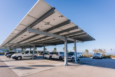 Endülüs, İspanya, 30 Ocak 2025 - Güneşli bir günde güneşli bir günde, etrafı palmiye ağaçları ve açık mavi gökyüzü ile çevrili, güneşle kaplı park yeri.