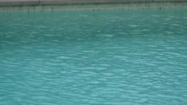 Yağmur damlaları yüzme havuzunun yüzeyine vurarak dalgalanmalar ve desenli bir su deseni oluşturdu. Kopyalama alanı olan sakin ve sakin bir atmosfer.