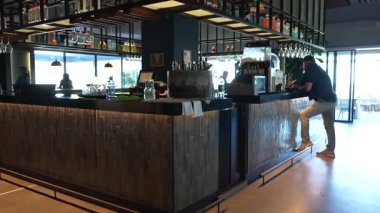 Endülüs, İspanya - 30 Ocak 2025 Modern bar iç mimarisi şık ışıklandırma, raflar dolusu şişe ve rahat bir atmosferde tezgaha yaslanan bir insan.