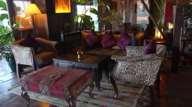Endülüs, İspanya - 30 Ocak 2025 - Leopar desenli sandalyeler, renkli yastıklar, antika bir masa, sıcak aydınlatma, bitkiler ve kırsal dekor aksanlı rahat, seçici bir yaşam alanı.