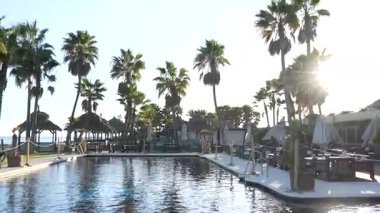 Endülüs, İspanya - 30 Ocak 2025 - Palmiye ağaçları, havuz, dinlenme alanları ve şemsiyelerle dolu tropik bir açık hava ortamı, sakin ve egzotik bir tatil havasını çağrıştırıyor..