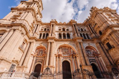 Endülüs, Malaga - 31 Ocak 2025 Malaga Katedrali 'nin büyük cephesi, karmaşık oymalar, uzun sütunlar, kemerli girişler ve bulutlu dramatik mavi bir gökyüzü..