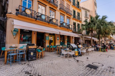 Endülüs, Malaga - 31 Ocak 2025 - Açık bir gökyüzü altında masaları, sandalyeleri, menüleri ve palmiye ağaçları olan renkli bir restoranın açık hava yemek alanı.